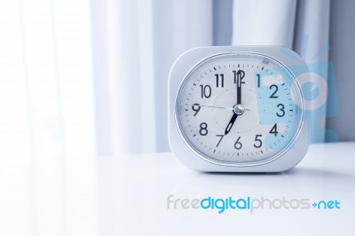 White Square Clock On White Bed Stand With White Curtain Background, Morning Time In Minimal Style Decoration Stock Photo