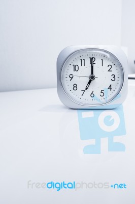 White Square Clock On White Bed Stand With White Wallpaper Background, Morning Time In Minimal Style Decoration Stock Photo