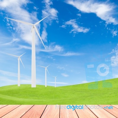 Wind Turbine On Green Grass Field And Blue Sky Background Stock Photo