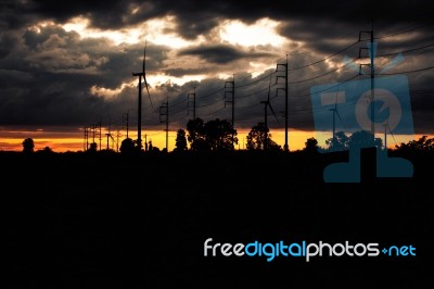 Wind Turbines And Electric Poles At Sunset Stock Photo