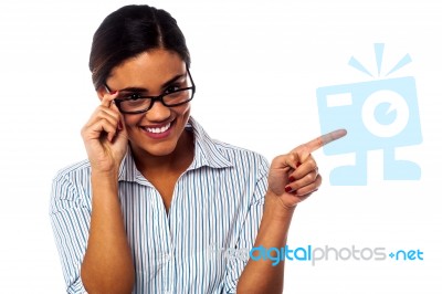 Woman Adjusting Her Spectacles And Pointing Away Stock Photo