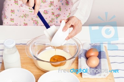 Woman Baking And Pouring Honey Into Milk Stock Photo