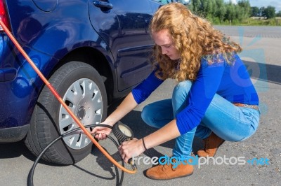 Woman Checking Air Pressure Of Car Tire Stock Photo