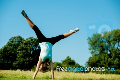 Woman Doing Cartwheel In A Field Stock Photo