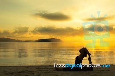 Woman Doing Yoga On The Beach Stock Photo