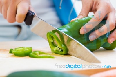 Woman Hand Cutting A Green Pepper In Kitchen Stock Photo