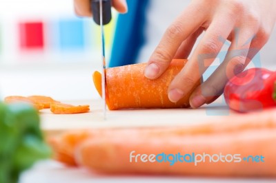 Woman Hand Cutting Carrots In Kitchen Stock Photo