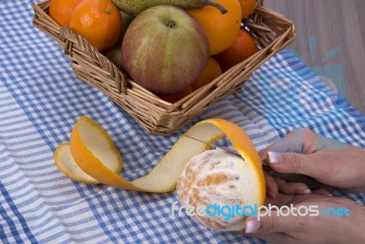 Woman Hands Peeling An Orange With A Knife Stock Photo