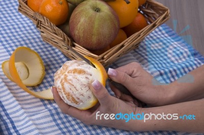 Woman Hands Peeling An Orange With A Knife Stock Photo