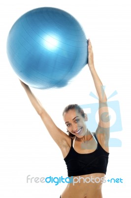 Woman Holding Big Blue Pilates Ball Above Her Head Stock Photo