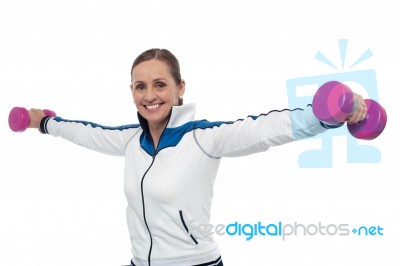 Woman Holding Dumbbells In Her Outstretched Arms Stock Photo