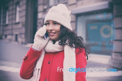 Woman In Red Coat And Wool Cap And Gloves With Smartphone In Han… Stock Photo