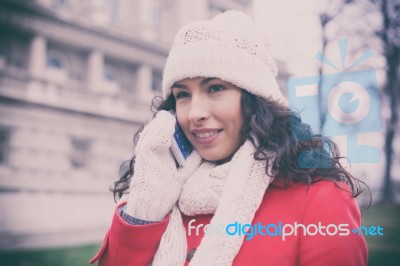 Woman In Red Coat And Wool Cap And Gloves With Smartphone In Han… Stock Photo