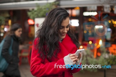 Woman In Red Coat Read Good News On Smartphone In Hands, Urban S… Stock Photo