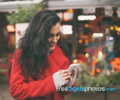 Woman In Red Coat Read Good News On Smartphone In Hands, Urban S… Stock Photo