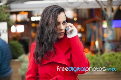 Woman In Red Coat Speak On Mobile Phone Stock Photo