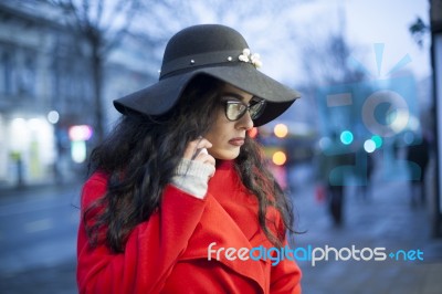 Woman In Red Coat With Smartphone In Hands Going Through The Cit… Stock Photo