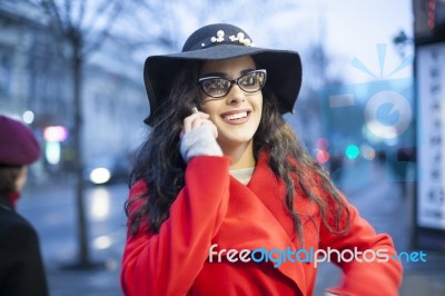 Woman In Red Coat With Smartphone In Hands Going Through The Cit… Stock Photo