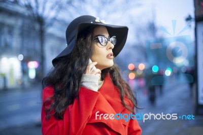 Woman In Red Coat With Smartphone In Hands Going Through The Cit… Stock Photo