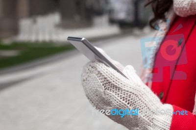 Woman In Red Coat With Smartphone In Hands Going Through The Cit… Stock Photo