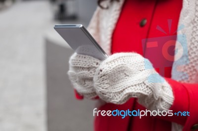 Woman In Red Coat With Smartphone In Hands Going Through The Cit… Stock Photo