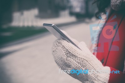 Woman In Red Coat With Smartphone In Hands Going Through The Cit… Stock Photo