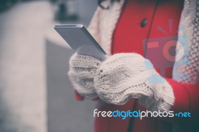 Woman In Red Coat With Smartphone In Hands Going Through The Cit… Stock Photo