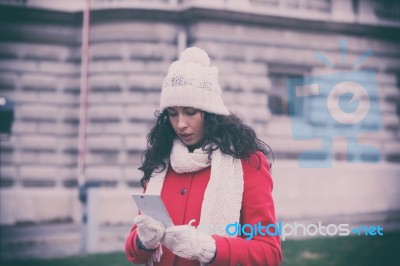 Woman In Red Coat With Smartphone In Hands Going Through The Cit… Stock Photo