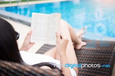 Woman In Summer Hat Reading A Book Near The Water Pool Wearing A… Stock Photo