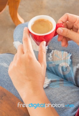 Woman In Torn Jeans Sitting At Coffee Shop Stock Photo