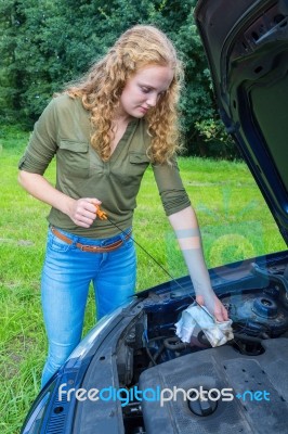 Woman Investigates Car Oil Level With Dipstick Stock Photo