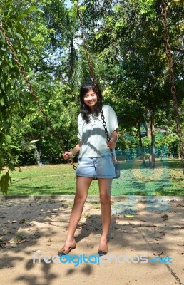 Woman Is Standing On A Swing In A Park Setting Stock Photo