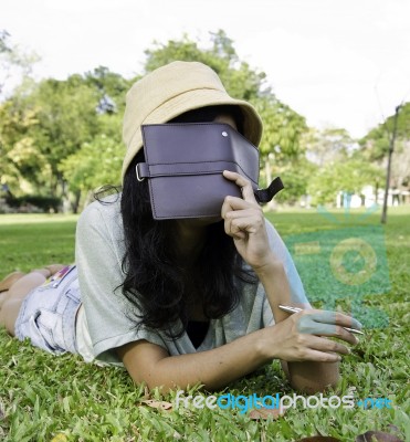 Woman Laying On Grass And Thinking In Park Stock Photo