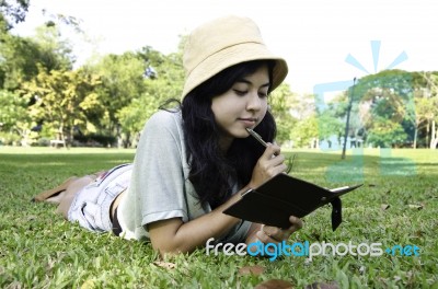 Woman Laying On Grass And Thinking In Park Stock Photo