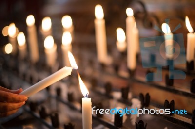 Woman Lighting Prayer Candle Stock Photo