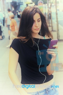 Woman Listens Music And Walks On The Street Stock Photo