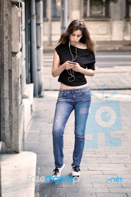 Woman Listens Music And Walks On The Street Stock Photo