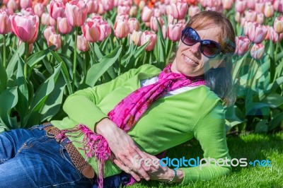 Woman Lying In Front Of Pink Tulip Field Stock Photo