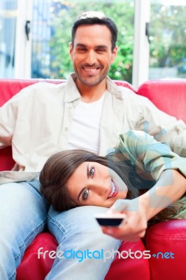 Woman Lying On Boyfriend's Lap While Using Remote Control Stock Photo