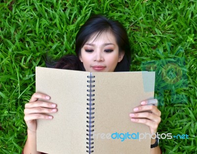 Woman Lying On Grass With  Book Stock Photo