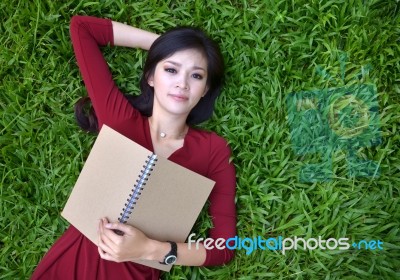 Woman Lying On Grass With  Book Stock Photo