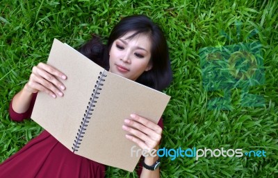 Woman Lying On Green Grass With  Book Stock Photo