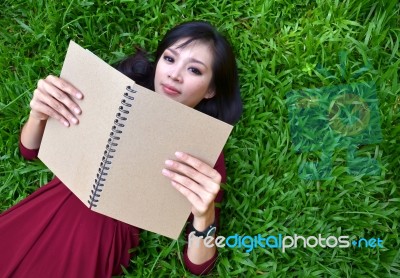 Woman Lying On Green Grass With  Book Stock Photo