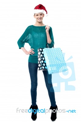 Woman Posing With Shopping Bags Wearing Santa Cap Stock Photo