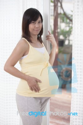 Woman Pregnant Standing Beside Home Door And Looking To Camera Stock Photo