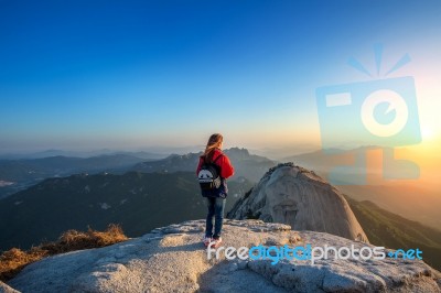 Woman Stands On The Peak Of Stone In Bukhansan National Park,seoul In South Korea And Watching To Sunrise. Beautiful Moment The Miracle Of Nature Stock Photo