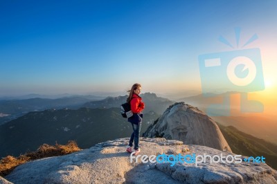 Woman Stands On The Peak Of Stone In Bukhansan National Park,seoul In South Korea And Watching To Sunrise. Beautiful Moment The Miracle Of Nature Stock Photo