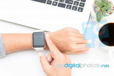 Woman Touching Smart Watch Hand On Work Desk Stock Photo