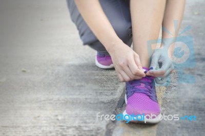 Woman Tying Her Shoes Preparing For A Jog Stock Photo