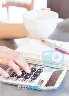 Woman's Hands Holding Coffee Cup And Press Calculator Stock Photo